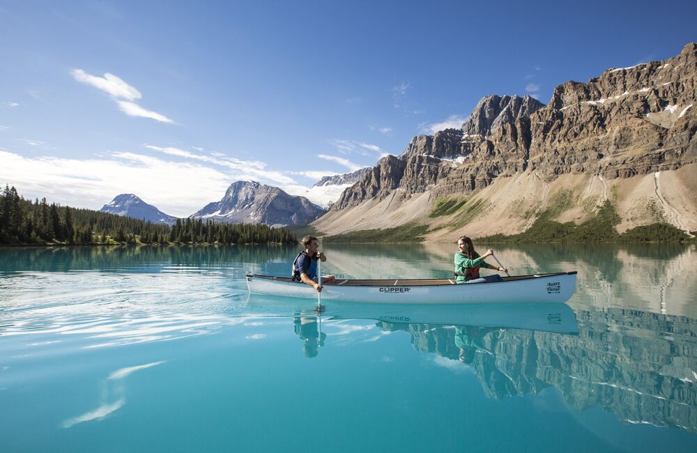 People paddling in a canoe on the turquoise waters of Bow Lake in the summer